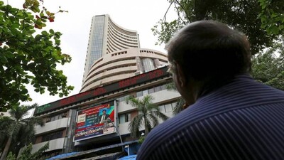 A man looks at a screen across a road displaying the Sensex on the facade of the Bombay Stock Exchange (BSE) building in Mumbai