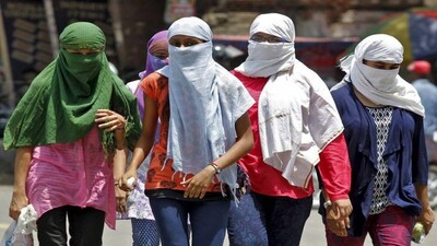 Girls, with faces covered to protect themselves from sun stroke, walk along a road on a hot summer day in Allahabad